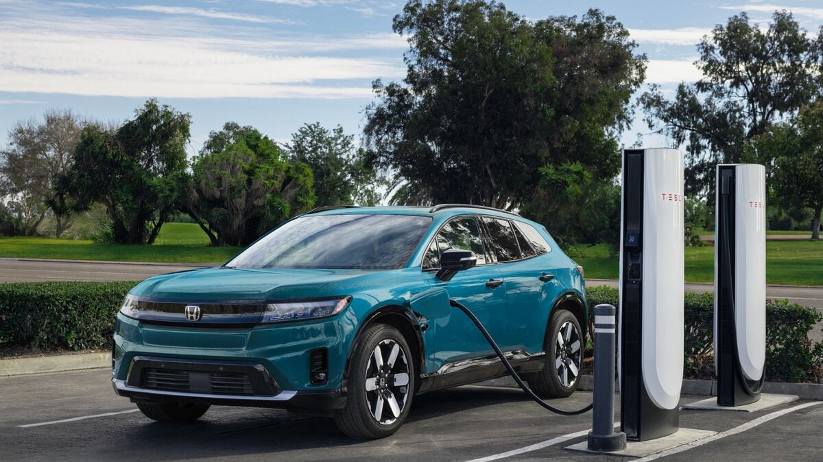 A 2025 Honda Prologue in blue charging from a Tesla Supercharger