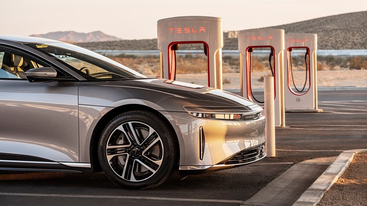 The 2026 Lucid Air in silver charging from a Tesla Supercharger