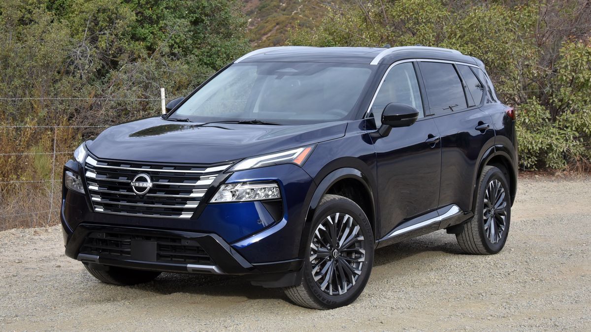 2025 Nissan Rogue parked by trees and bushes.