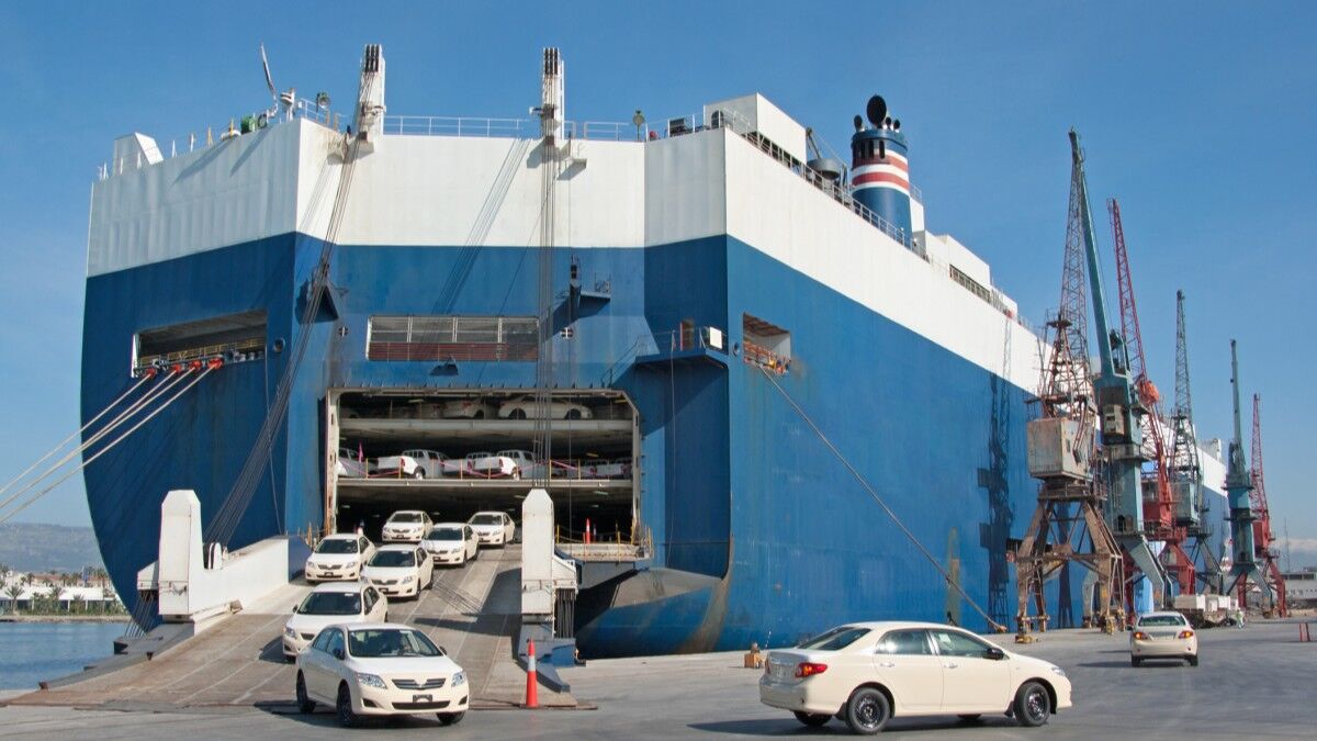 New cars drive off a roll-on/roll-off container ship in a port
