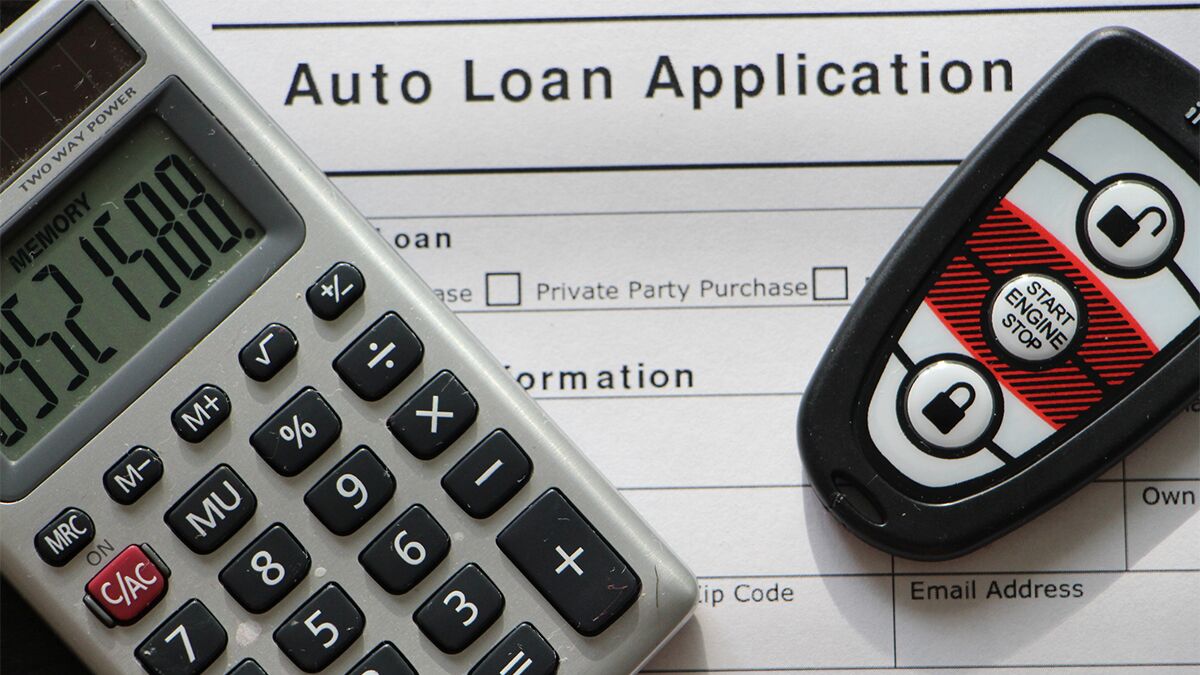 A calculator and a car's keyfob rest on an auto loan application form