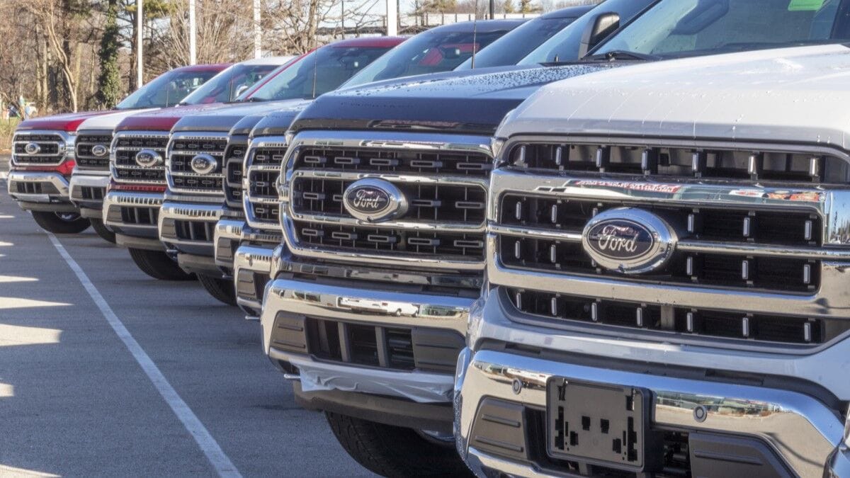 A line of F-150 pickups parked in a Ford dealership lot