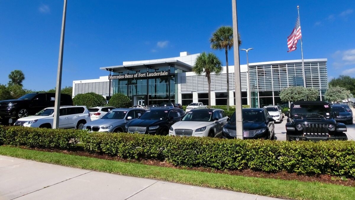 Cars lined up outside a Mercedes-Benz dealership in Florida with palm trees