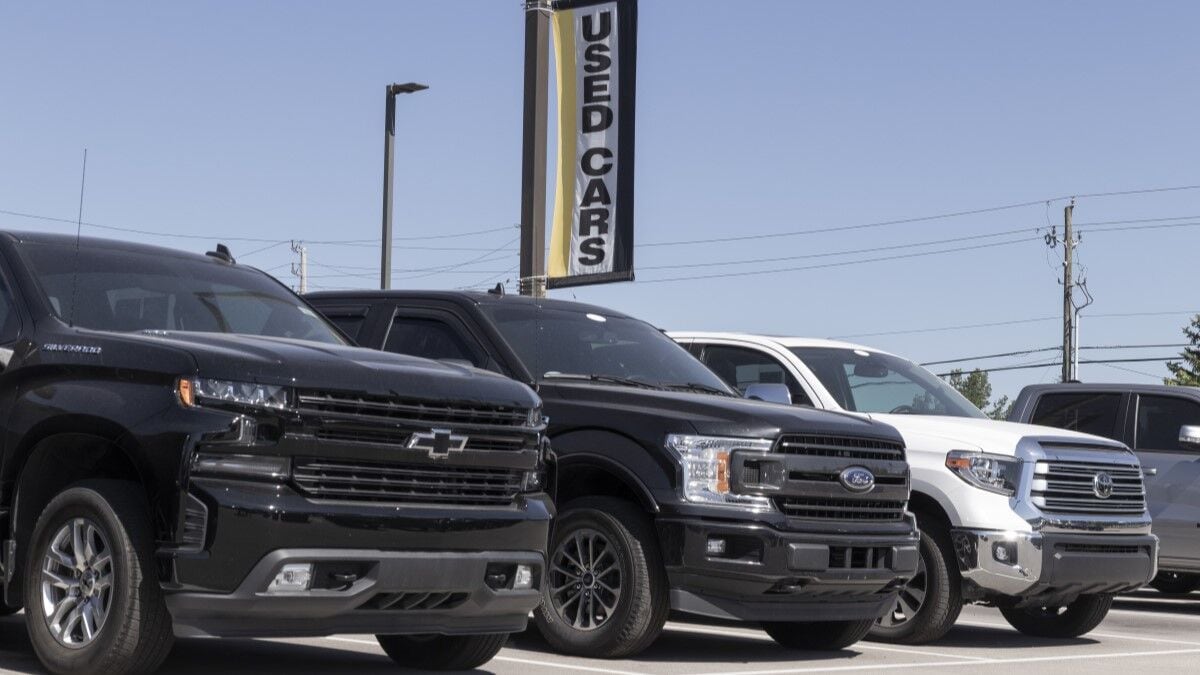 Trucks from several brands lined up for sale at a used car dealership