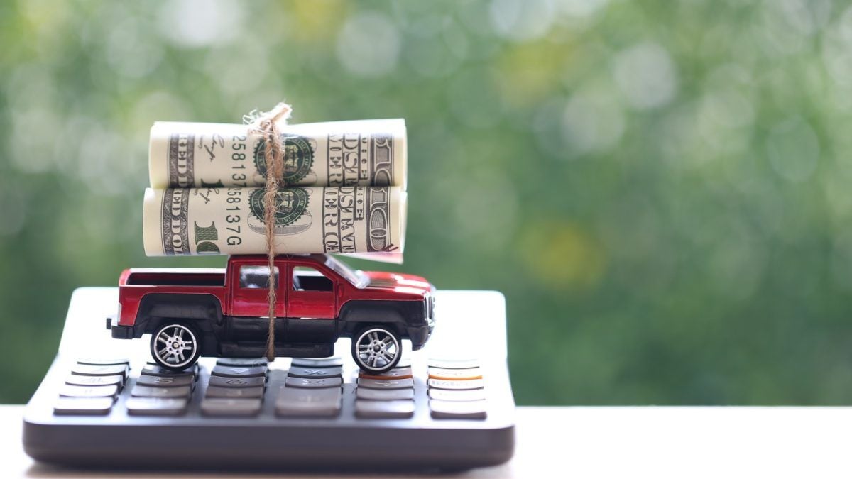 A pile of cash tied to a toy truck atop a calculator