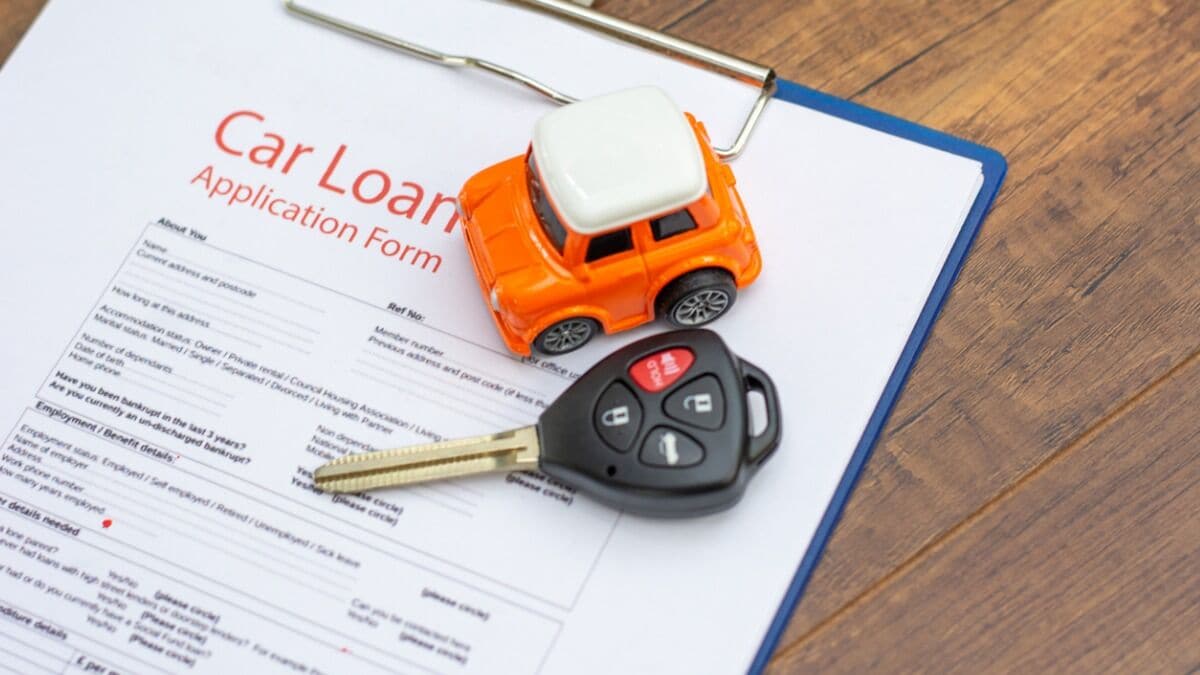 A car loan application sits beneath a toy car and a car key