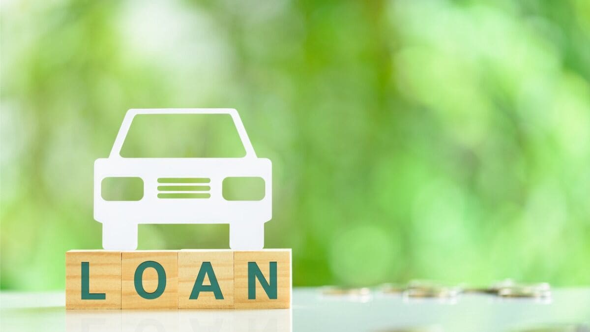 A paper cutout of a car sits on toy blocks spelling out the word LOAN