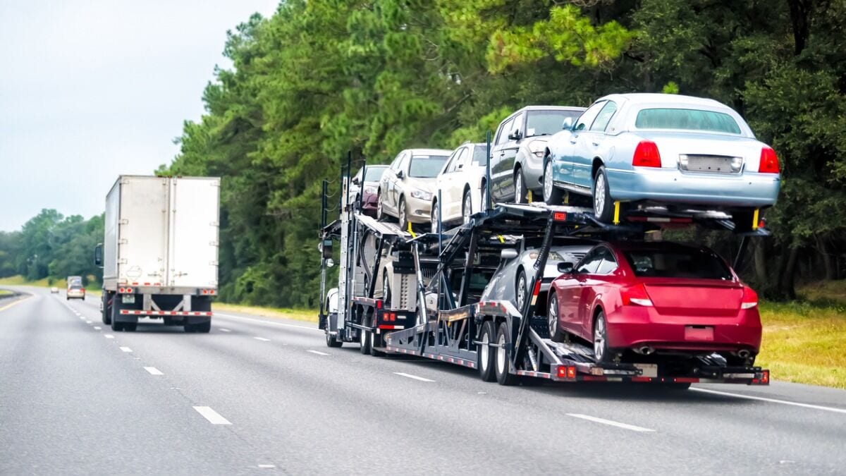 A car carrier loaded with cars travels on a highway